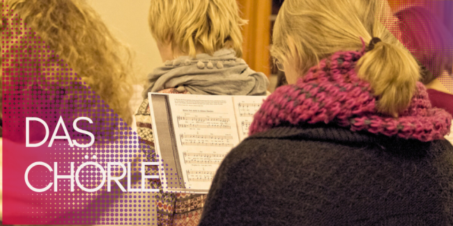 Frauen von hinten mit Notenblättern vor sich.